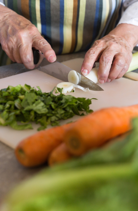 close-up-of-a-senior-lady-cutting-vegetables-on-a-PSRBJBT 1